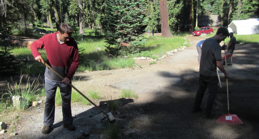 Outward Bound students use gardening tools to work on a trail during a service day